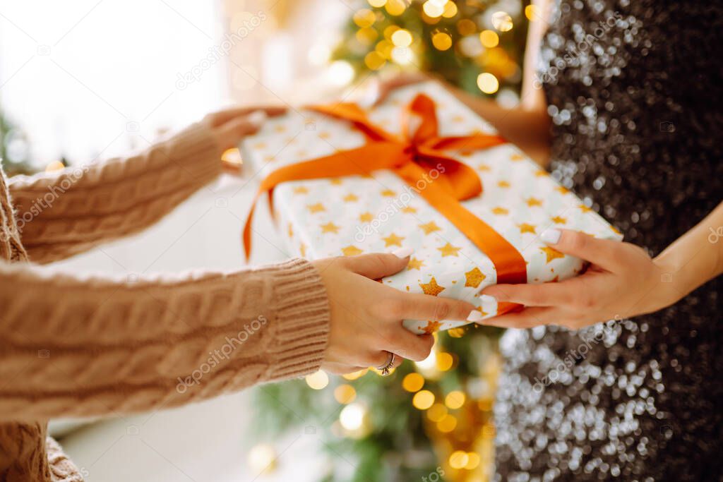 Gives the gift. Exchanging the christmas presen. Young woman gives a gift in a box. Winter holiday, New Year, celebration, birthday concept.
