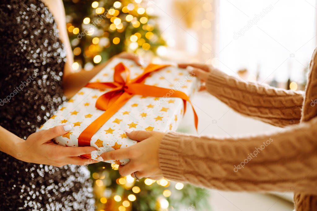 Gives the gift. Exchanging the christmas presen. Young woman gives a gift in a box. Winter holiday, New Year, celebration, birthday concept.