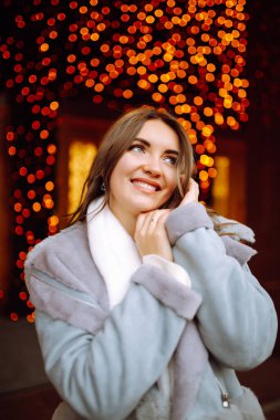 Güzel bir kadın Noel pazarında kış tatillerinin tadını çıkarır. Şenlik sokağında poz veren genç bir kadın. Yeni Yıl.