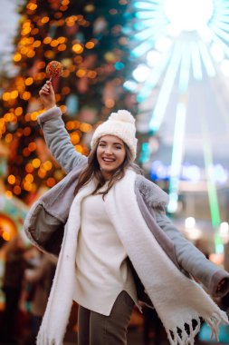 Noel Festivali 'nde karamelli elmalı mutlu kadın. Güzel bir kadın Noel pazarında kış tatilinin tadını çıkarır. Yeni yıl. Işıklar yanıyor..