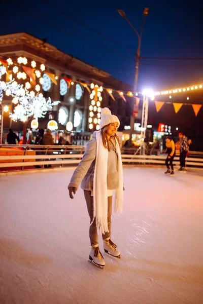 クリスマス イブの冬には 市内広場の氷のアリーナで幸せな女性のアイススケート 美しい女性はクリスマスマーケットで冬の休暇を楽しんでいます 年末年始のライトアップ — ストック写真