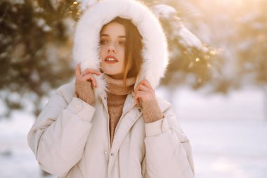 Karlı bir parkta poz veren güzel bir kadın. Soğuk hava. Kış modası, tatiller, dinlenme, seyahat konsepti.