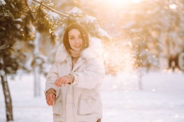 Karlı bir parkta poz veren güzel bir kadın. Soğuk hava. Kış modası, tatiller, dinlenme, seyahat konsepti.