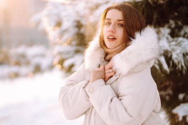 Karlı bir parkta poz veren güzel bir kadın. Soğuk hava. Kış modası, tatiller, dinlenme, seyahat konsepti.