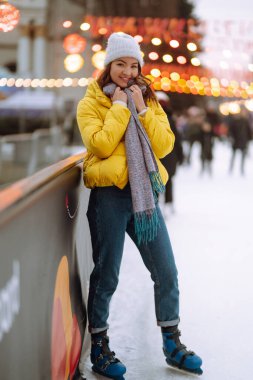 Mutlu kadın Noel Festivali 'nde şehir meydanında buz pateni yapıyor. Soğuk hava. Kış modası, tatiller, aktif konsept.