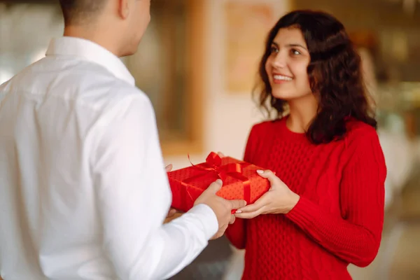 Exchange of gifts.  Young couple in love offering gift to each other for valentine day or birthday. Romantic day. Winter holidays.