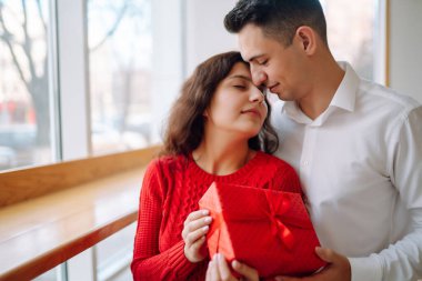 Hediye kutusuyla sarılıp Sevgililer Günü 'nü kutlayan genç bir çift. İlişki, tatil, sürpriz ve aşk kavramı.