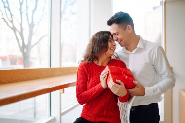 Hediye kutusuyla sarılıp Sevgililer Günü 'nü kutlayan genç bir çift. İlişki, tatil, sürpriz ve aşk kavramı.