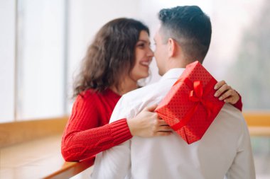 Hediye kutusuyla sarılıp Sevgililer Günü 'nü kutlayan genç bir çift. İlişki, tatil, sürpriz ve aşk kavramı.