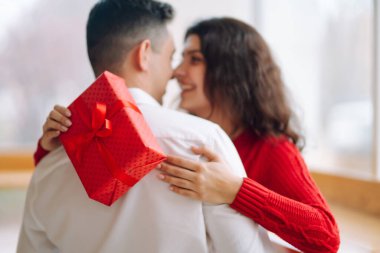 Hediye kutusuyla sarılıp Sevgililer Günü 'nü kutlayan genç bir çift. İlişki, tatil, sürpriz ve aşk kavramı.