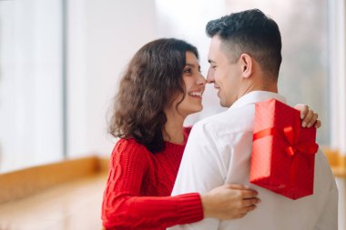 Hediye kutusuyla sarılıp Sevgililer Günü 'nü kutlayan genç bir çift. İlişki, tatil, sürpriz ve aşk kavramı.