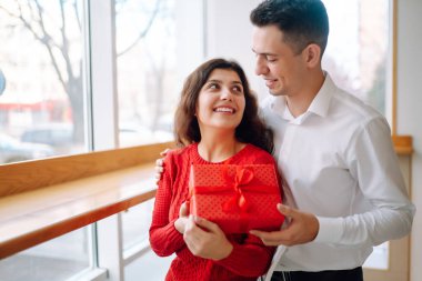 Hediye kutusuyla sarılıp Sevgililer Günü 'nü kutlayan genç bir çift. İlişki, tatil, sürpriz ve aşk kavramı.