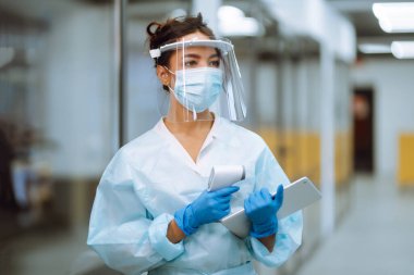 Hastalık kontrol uzmanı vizör ve koruyucu eldiven ve kızılötesi termometre cihazıyla karantinadaki salgın sırasında ofisteki sıcaklığı kontrol ediyor. COVID-19.