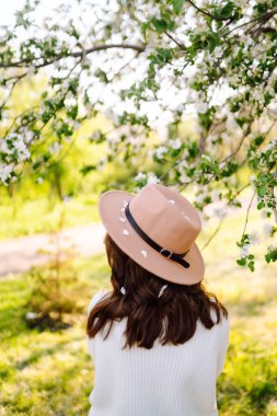 Bahar çiçeklerinde çiçek açan bahçede poz veren genç bir kadın. Kadın güzelliği, moda. Şehir yaşam tarzı.