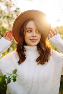 Bahar çiçeklerinde çiçek açan bahçede poz veren genç bir kadın. Kadın güzelliği, moda. Şehir yaşam tarzı.