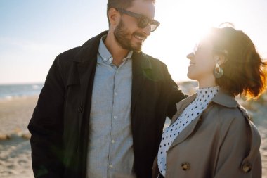 Deniz kenarında yürüyen ve kucaklaşan şık bir çift. Hoş hippi çift birlikte eğleniyor. Gençlik, aşk ve yaşam tarzı kavramı. İlkbahar.