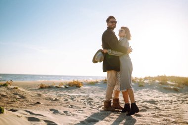 Deniz kenarında yürüyen ve kucaklaşan şık bir çift. Hoş hippi çift birlikte eğleniyor. Gençlik, aşk ve yaşam tarzı kavramı. İlkbahar.