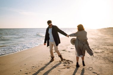 Deniz kenarında yürüyen ve kucaklaşan şık bir çift. Hoş hippi çift birlikte eğleniyor. Gençlik, aşk ve yaşam tarzı kavramı. İlkbahar.