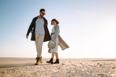 Deniz kenarında yürüyen ve kucaklaşan şık bir çift. Hoş hippi çift birlikte eğleniyor. Gençlik, aşk ve yaşam tarzı kavramı. İlkbahar.