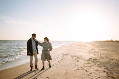 Deniz kenarında yürüyen ve kucaklaşan şık bir çift. Hoş hippi çift birlikte eğleniyor. Gençlik, aşk ve yaşam tarzı kavramı. İlkbahar.