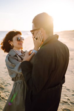 Deniz kenarında yürüyen ve kucaklaşan şık bir çift. Hoş hippi çift birlikte eğleniyor. Gençlik, aşk ve yaşam tarzı kavramı. İlkbahar.