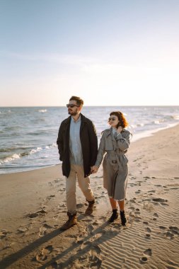Deniz kenarında yürüyen ve kucaklaşan şık bir çift. Hoş hippi çift birlikte eğleniyor. Gençlik, aşk ve yaşam tarzı kavramı. İlkbahar.