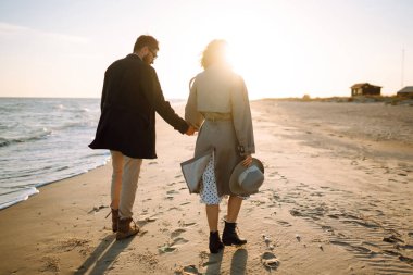 Deniz kenarında yürüyen ve kucaklaşan şık bir çift. Hoş hippi çift birlikte eğleniyor. Gençlik, aşk ve yaşam tarzı kavramı. İlkbahar.