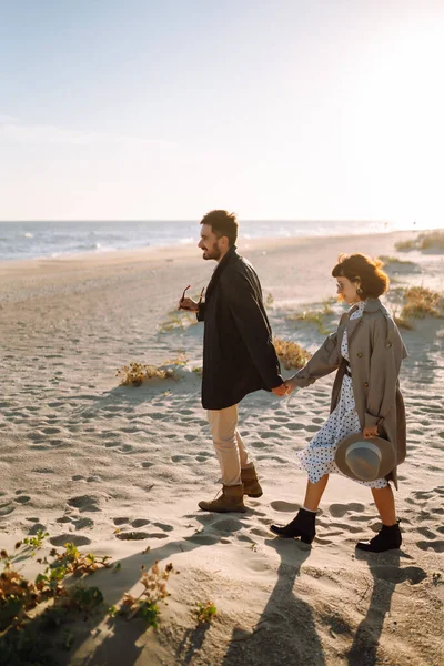 Stylish couple walking and hugging by the sea. Lovely hipster couple enjoying time together. The concept of youth, love and lifestyle. Springtime.