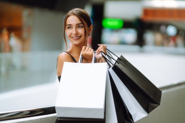 Alışveriş merkezinde yürüdükten sonra genç bir kadın. Tüketim, alım, kara Cuma, indirimler, satış konsepti..