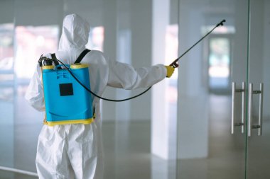 Koruyucu giysinin içindeki bir dezenfektan ve maske ofiste dezenfektan püskürtür. COVID-19 hastalığını koruma amaçlı. Yüzeyleri olan zatürree virüsünün yayılmasının önlenmesi.