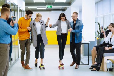 Bir grup iş arkadaşı ofiste kaykayla eğleniyor. İş arkadaşları ofiste kaykay yaparken tezahürat yapıyorlar.. 