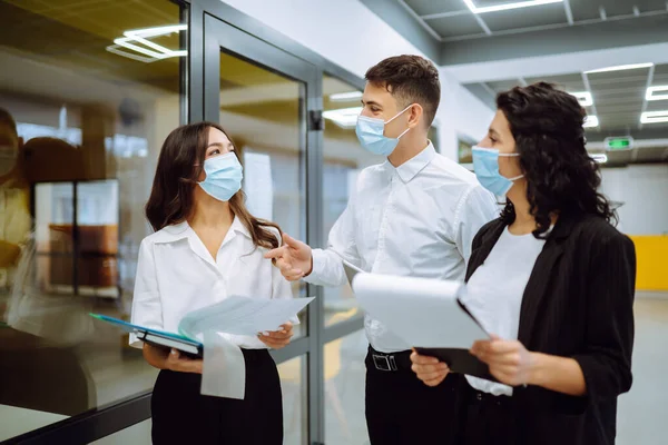 Business colleagues in protective face mask  discussing together work issues. Teamwork of Business people during pandemic of coronavirus. Covid-19.