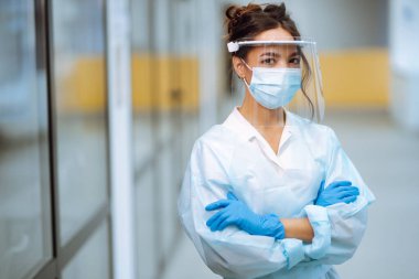 Ofisteki sıcaklığı kontrol etmek için kızılötesi termometre cihazıyla vizör ve koruyucu eldivenler konusunda uzman. Covid 19.