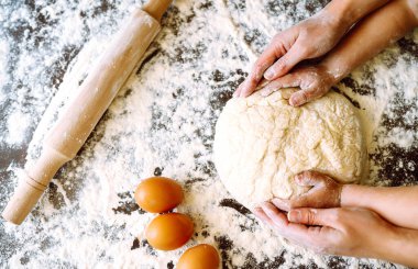 Anne ve oğlunun elleri hamuru birlikte yoğuruyor. Evde aile yemekleri. Paskalya pastası hazırlığı. Noel için kurabiyeler.