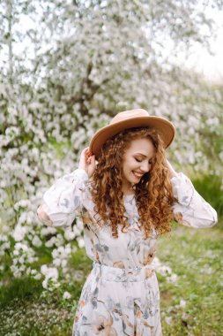 Lanet bahar parkında poz veren şapkalı kıvırcık kadın. Rahatlama, seyahat, cennet, romantizm ve bahar tatili kavramı. Moda tarzı.
