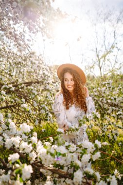 Lanet bahar parkında poz veren şapkalı kıvırcık kadın. Rahatlama, seyahat, cennet, romantizm ve bahar tatili kavramı. Moda tarzı.