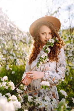 Lanet bahar parkında poz veren şapkalı kıvırcık kadın. Rahatlama, seyahat, cennet, romantizm ve bahar tatili kavramı. Moda tarzı.