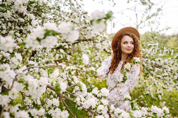 Lockig Kvinna Med Hatt Poserar Blommande Vårpark Begreppet Avkoppling Resor — Stockfoto