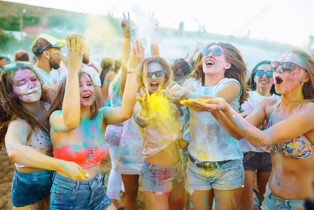 Group of people have fun at the holi festival of colors. Smiling faces in colorful powder. Celebrating traditional indian spring holiday. Party, vacation concept. Friendship and celebration concept.