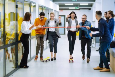 Bir grup iş arkadaşı yaratıcı ofiste kaykayla eğleniyor. Genç meslektaşlarım kaykay yapıyor. Arkadaş canlısı çalışma ekibi pozitif duyguların tadını çıkarıyor.