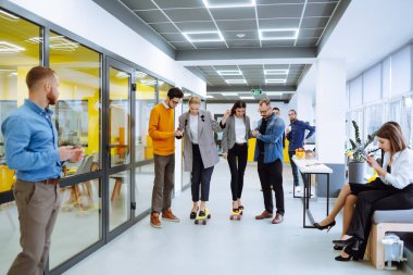 Bir grup iş arkadaşı yaratıcı ofiste kaykayla eğleniyor. Genç meslektaşlarım kaykay yapıyor. Arkadaş canlısı çalışma ekibi pozitif duyguların tadını çıkarıyor.