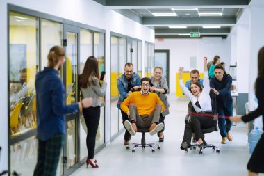 Dost canlısı çalışma ekibi ofis odasında sandalyeye biniyor çeşitli çalışanlar eğlenirken eğleniyor ve eğleniyor yaratıcı çalışanlar birlikte oyun oynuyor..