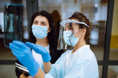 Vizörlü, koruyucu eldivenli genç bir doktor ve röntgen çeken bir hasta. Pnömonia.lşık röntgenleri. Florografi. Covid 2019