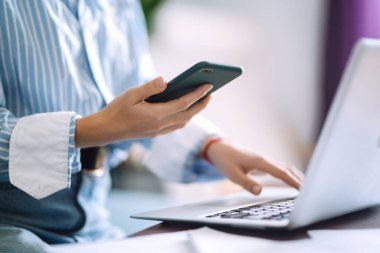 Karantina odasında çalışırken cep telefonu kullanan genç bir kadın. Sosyal ağda arkadaşlarıyla sohbet ediyor, internetten alışveriş yapıyor, telefon kullanarak e-posta yazıyor. Sosyal uzaklık. Kişisel İzolasyon