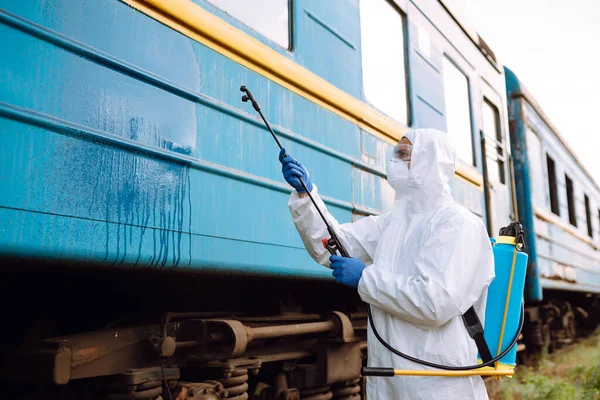 Man wearing protective suit disinfecting public a train with spray chemicals to preventing the spread of coronavirus, pandemic in quarantine city. Covid -19. Cleaning concept.