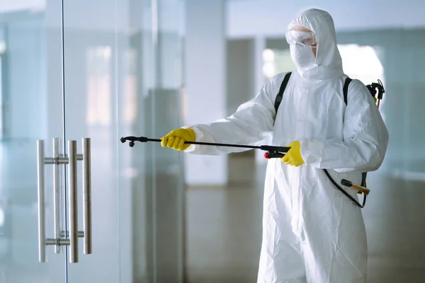 Covid 19を防ぐためにオフィスの消毒 コロナウイルスの拡散を防ぐためにスプレー化学薬品で保護ハズマットスーツの男 検疫都市でのパンデミック — ストック写真