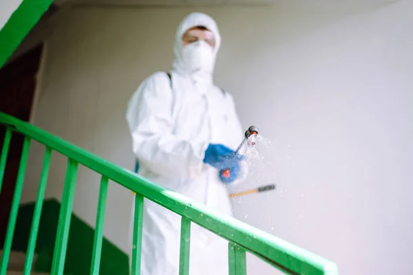 防護服を着た男は コロナウイルスの拡散を防ぐためにスプレー化学物質で住宅の建物の入り口を消毒します Covid 清掃コンセプト — ストック写真