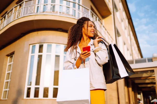 Jonge Vrouw Met Boodschappentassen Die Straat Met Een Mobiele Telefoon — Stockfoto