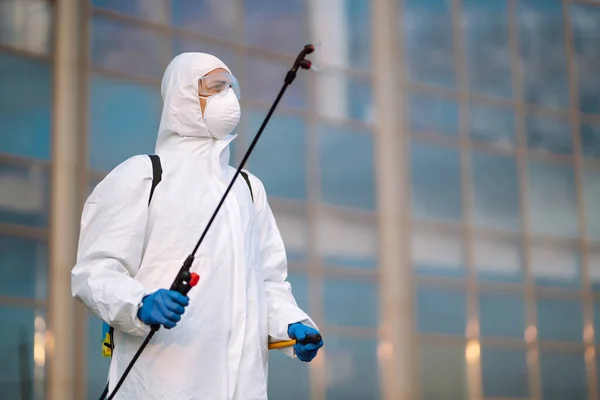 COVID-19 'u önlemek için koruyucu koruyucu koruyucu koruyucu koruyucu giysili bir adam koronavirüsün yayılmasını önlemek için sprey kimyasallarla dezenfekte ediyor. Temizlik kavramı.
