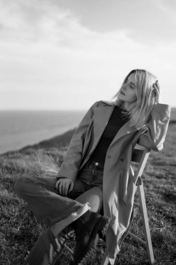 Güzel genç bayanın siyah beyaz fotoğrafı güneşli bir bahar gününün tadını çıkarıyor. İnsanlar, yaşam tarzı, seyahat, doğa ve tatil kavramı.